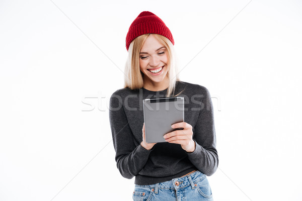 Smiling casual girl in hat standing and using tablet device Stock photo © deandrobot