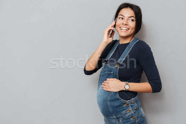 Happy pregnant woman talking by mobile phone Stock photo © deandrobot
