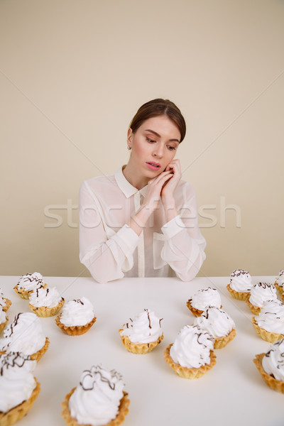 Pensive pretty young woman sitting at the table with cakes Stock photo © deandrobot