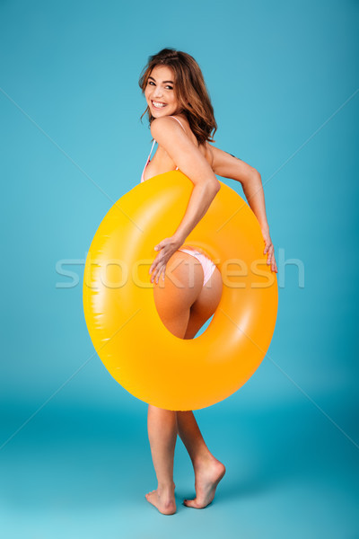 Vedere din spate zâmbitor fată costum de baie prezinta gonflabile Imagine de stoc © deandrobot