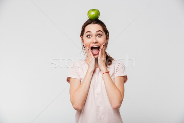 Portrait of an excited girl holding apple on her head Stock photo © deandrobot