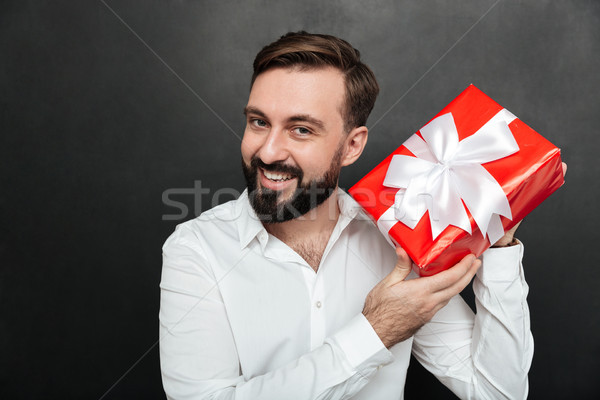 Portrait of curious man shaking red box gift wrapped, and trying Stock photo © deandrobot