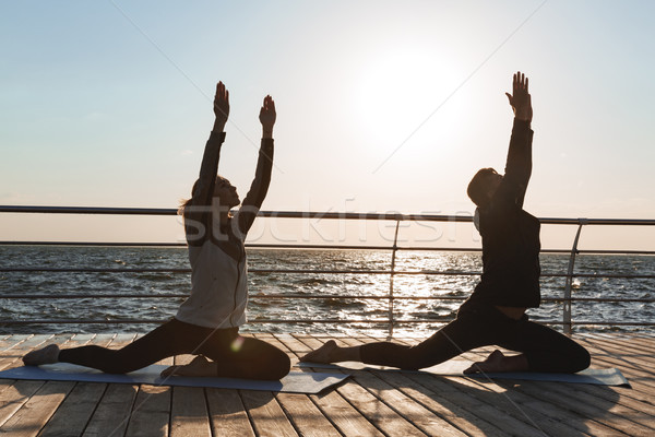 Healthy young sports couple practicing yoga together Stock photo © deandrobot
