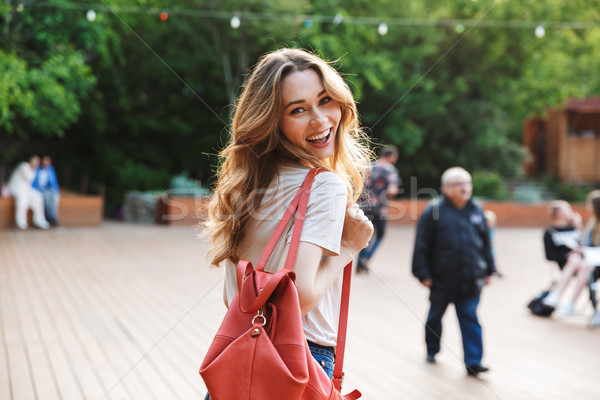 Smiling young woman with backpack walking Stock photo © deandrobot