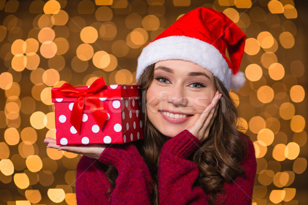 Dreaming smiling woman holding gift on palm over glittering background Stock photo © deandrobot