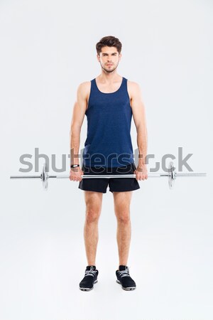 Cheerful young sportsman standing and lifting barbell Stock photo © deandrobot