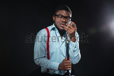 Stylish afro amerian man singing into vintage microphone Stock photo © deandrobot