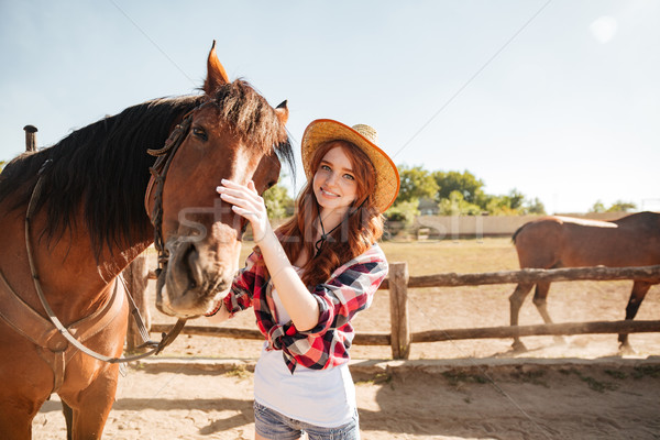 Happy woman cowgirl taking care of her horse on ranch Stock photo © deandrobot