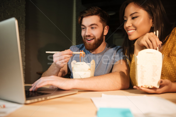 Two emotional colleagues working at night in office while eating Stock photo © deandrobot