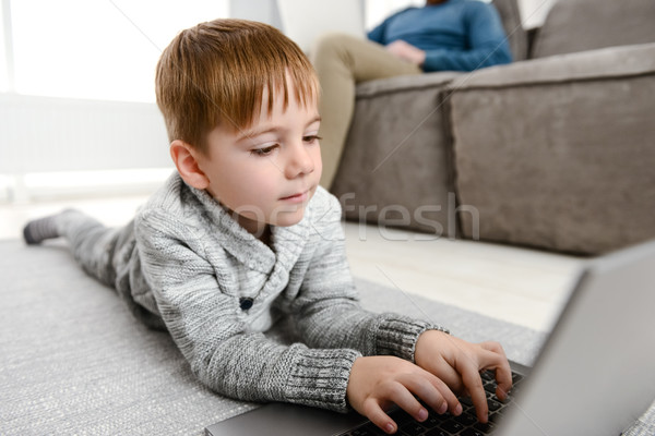 Drăguţ copil folosind laptop lies podea Imagine de stoc © deandrobot