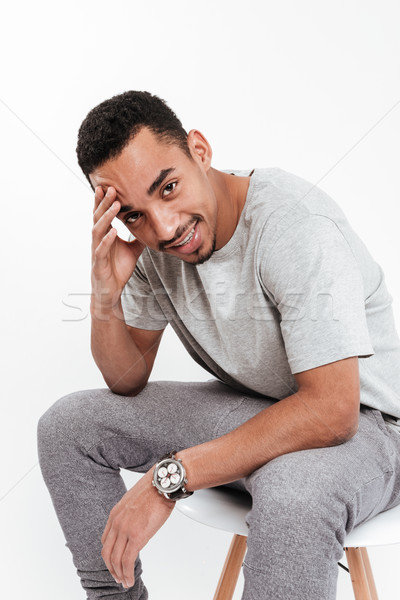 Handsome african man sitting over white background Stock photo © deandrobot