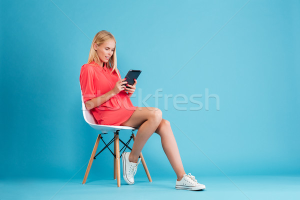 Concetrated casual woman in red dress using tablet Stock photo © deandrobot