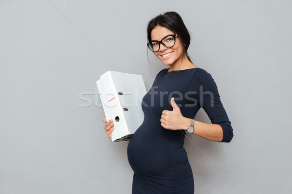 Happy pregnant business woman make thumbs up. Stock photo © deandrobot