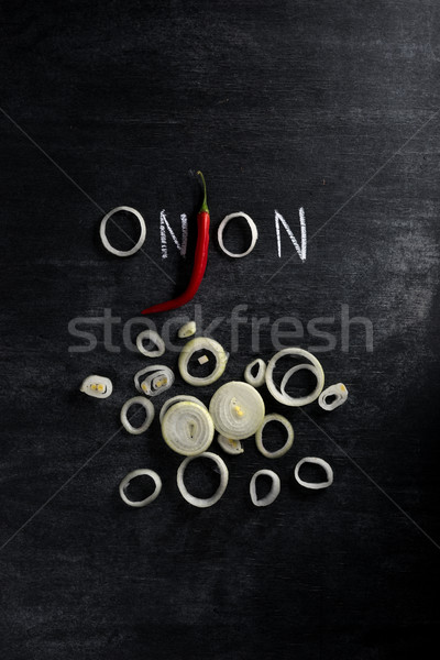 Cut onion and chilli pepper over dark chalkboard background Stock photo © deandrobot