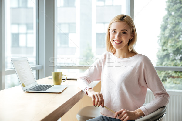 Cheerful lady sitting in office coworking while using laptop Stock photo © deandrobot