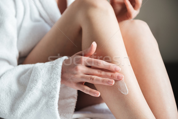 Closeup photo of woman smearing cream on her leg Stock photo © deandrobot