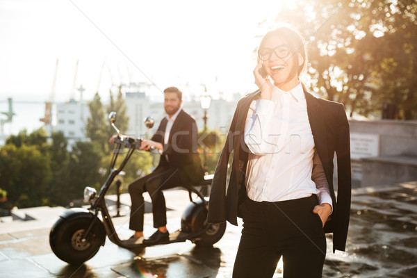 Happy business woman posing outdoors and talking by smartphone Stock photo © deandrobot