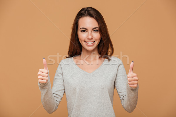 Close-up photo of pretty young woman in gray blouse showing thum Stock photo © deandrobot