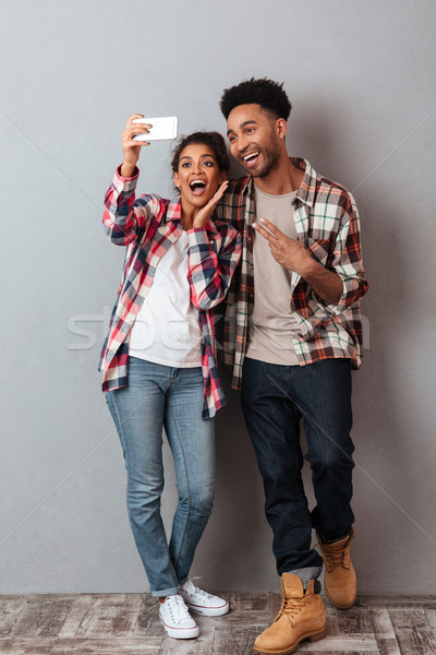 Portrait of a happy young african couple grimacing Stock photo © deandrobot