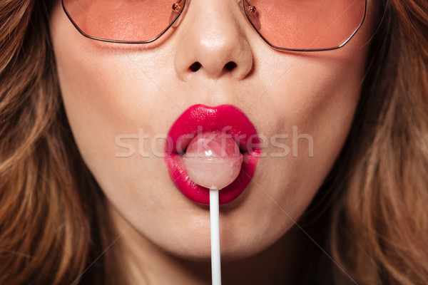 Cropped image of young beautiful lady eating candy. Stock photo © deandrobot
