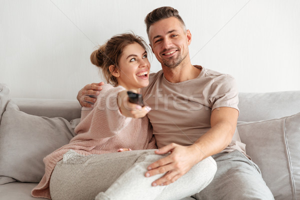 Portrait of a happy young couple sitting on a couch together Stock photo © deandrobot