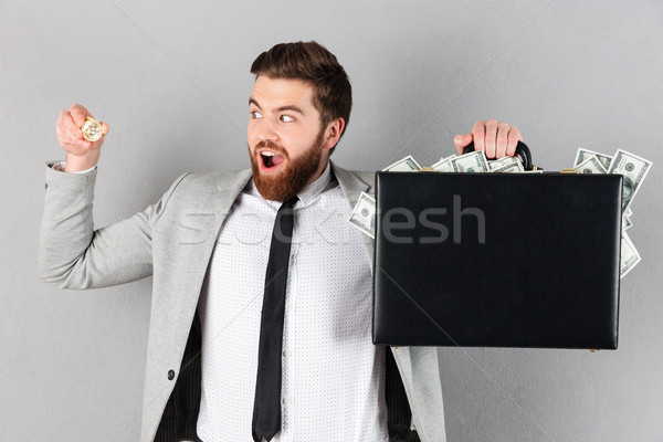 Portrait of a joyful businessman showing golden bitcoin Stock photo © deandrobot