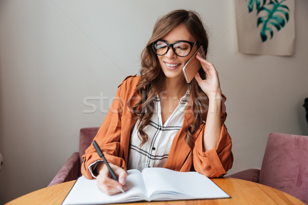 Portrait of a happy woman taking notes Stock photo © deandrobot