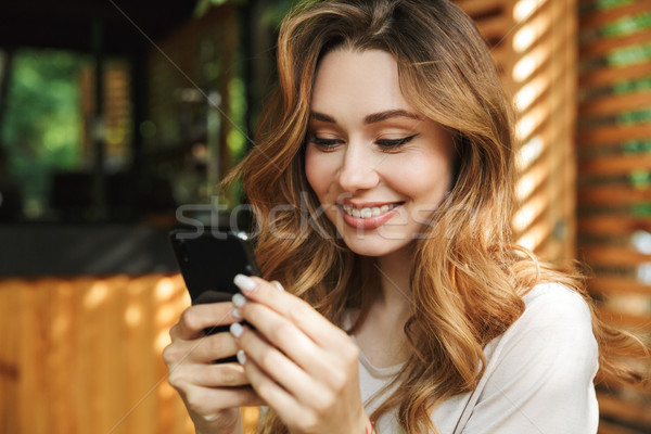 Close up portrait of a smiling young girl using mobile phone Stock photo © deandrobot