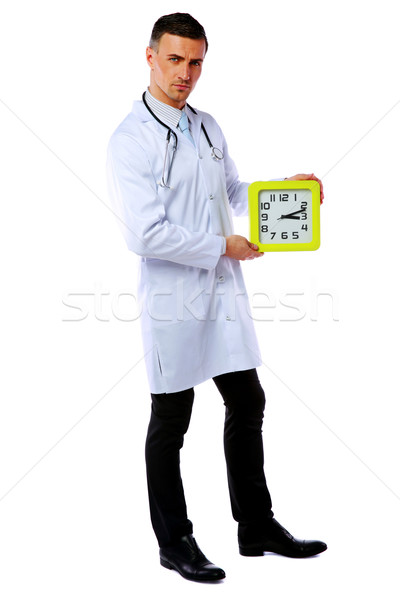 Confident male doctor holding clock isolated on white background Stock photo © deandrobot