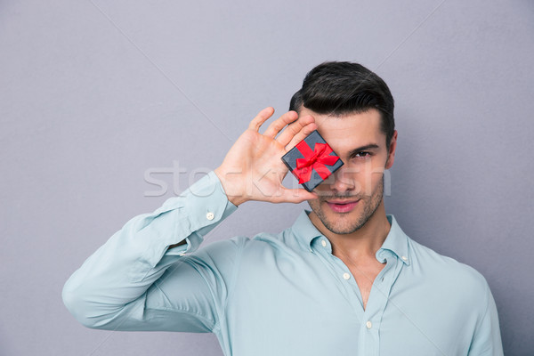 Young man covering his eye with gift box Stock photo © deandrobot