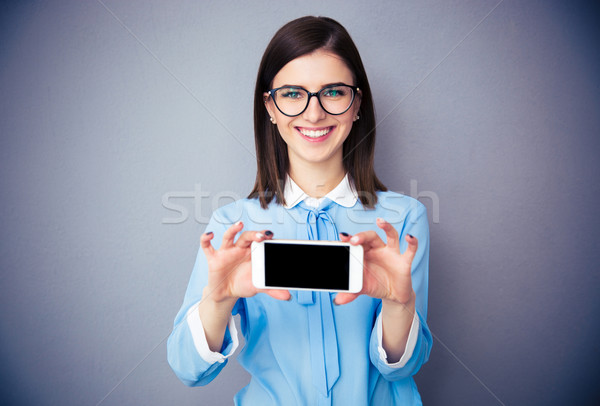 [[stock_photo]]: Souriant · femme · d'affaires · smartphone · écran · gris