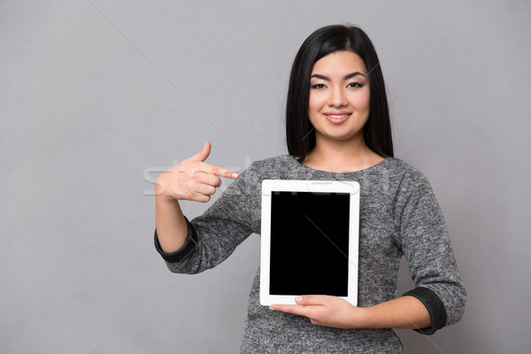 Asian girl staying and pointing on tablet Stock photo © deandrobot