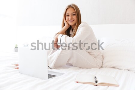 Happy woman holding pillow on the bed Stock photo © deandrobot