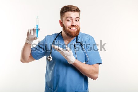 Happy male doctor pointing pen at camera Stock photo © deandrobot