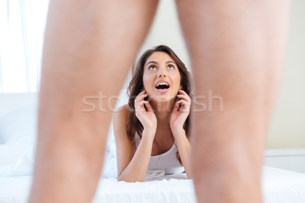 Woman lying in bed looking scared to men's genital Stock photo © deandrobot