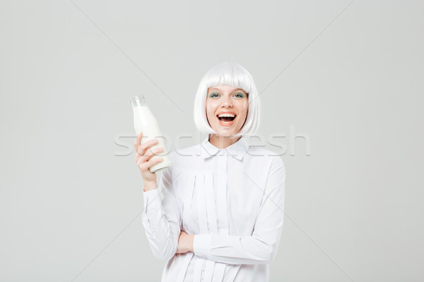 Cheerful beautiful young woman laughing and holding bottle of milk Stock photo © deandrobot