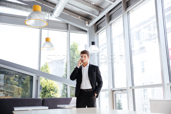 Businessman standing and talking on cell phone in cafe Stock photo © deandrobot
