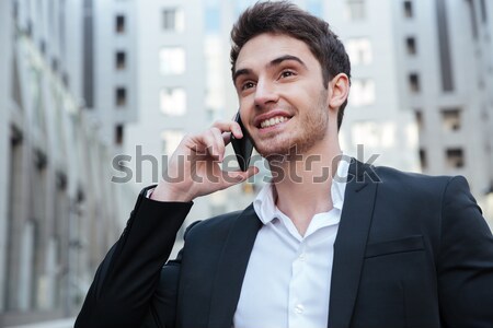 Happy young businessman talking on mobile phone in the city Stock photo © deandrobot