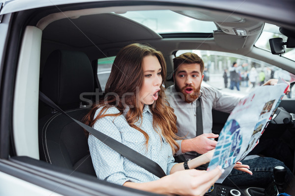 Surprised couple in car with map Stock photo © deandrobot
