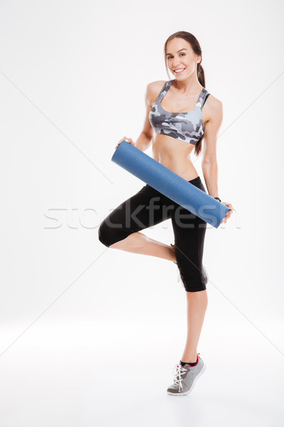 Full length of happy fitness woman with mat Stock photo © deandrobot