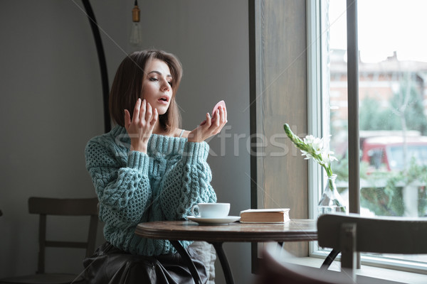 Beautiful young lady in cafe looking at mirror. Stock photo © deandrobot
