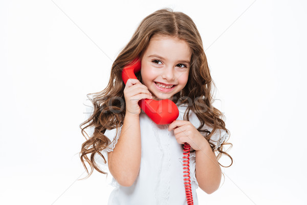 Happy curly little girl standing and talking on red telephone Stock photo © deandrobot