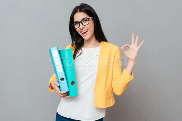 Young pretty woman holding folders and make okay gesture Stock photo © deandrobot
