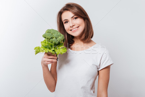 Cheerful young lady holding broccoli Stock photo © deandrobot