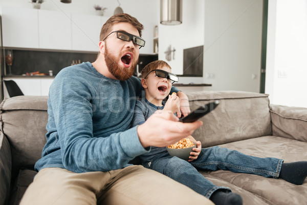 Surprised young father watching TV with his little cute son Stock photo © deandrobot