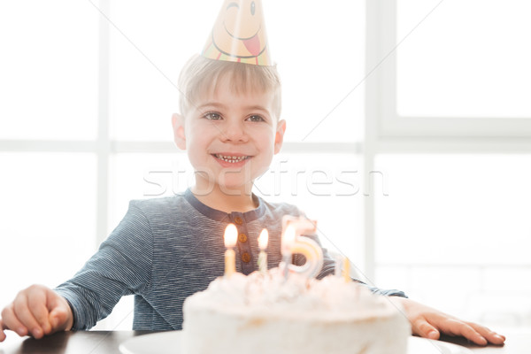 Cute happy birthday boy sitting in kitchen near cake Stock photo © deandrobot