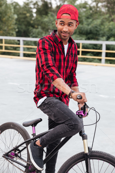 Happy dark skinned guy sitting on bicycle Stock photo © deandrobot