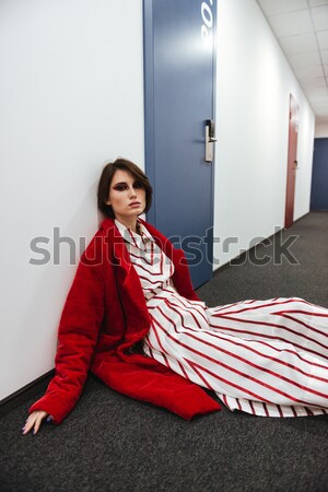 Beautiful young woman in red coat standing at corridor Stock photo © deandrobot