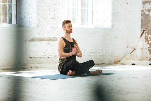 Young candid man sitting on a fitness mat Stock photo © deandrobot