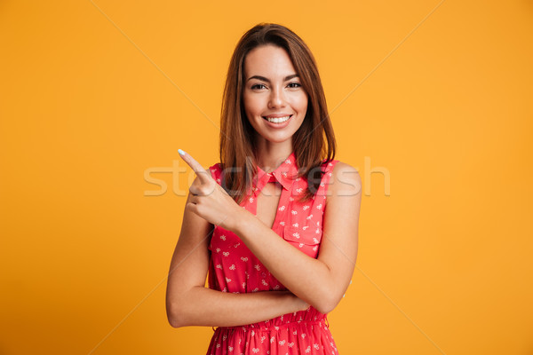 Pleased brunette woman in dress winks and pointing up Stock photo © deandrobot